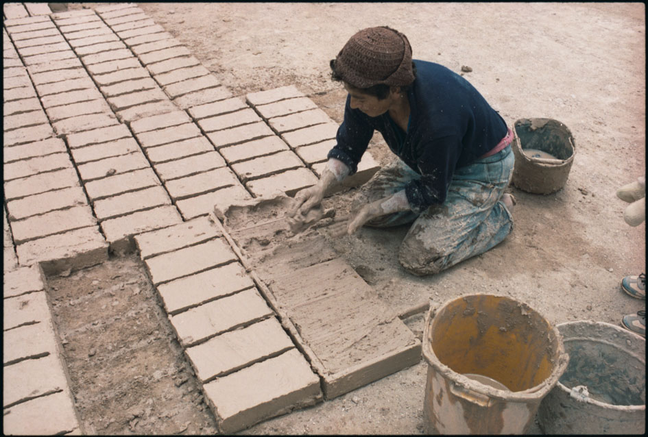 Fotografía de mujer trabajando en la fabricación de ladrillos artesanales 